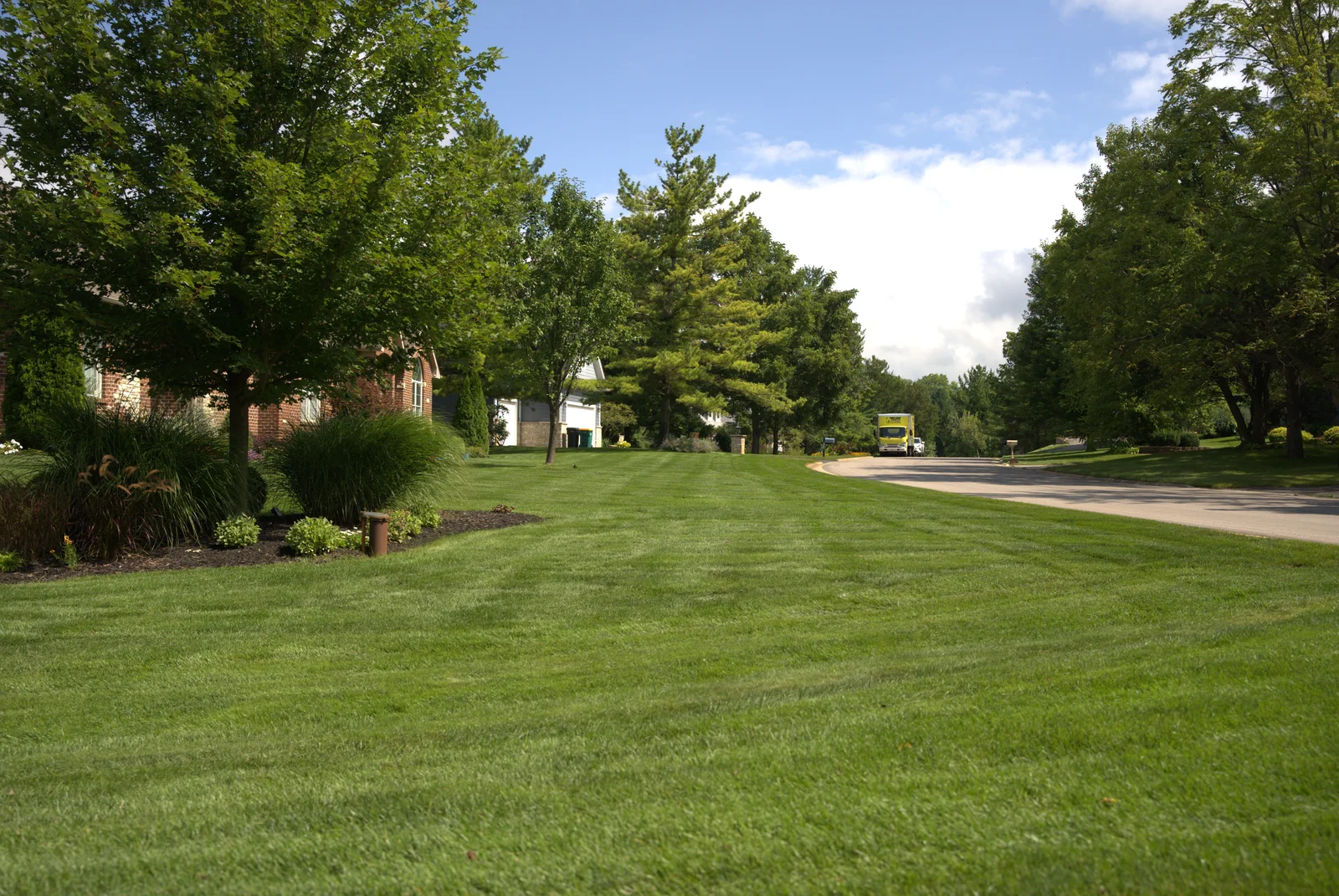 Green Acres professionally mowed residential lawn with clean striping pattern and landscaped beds