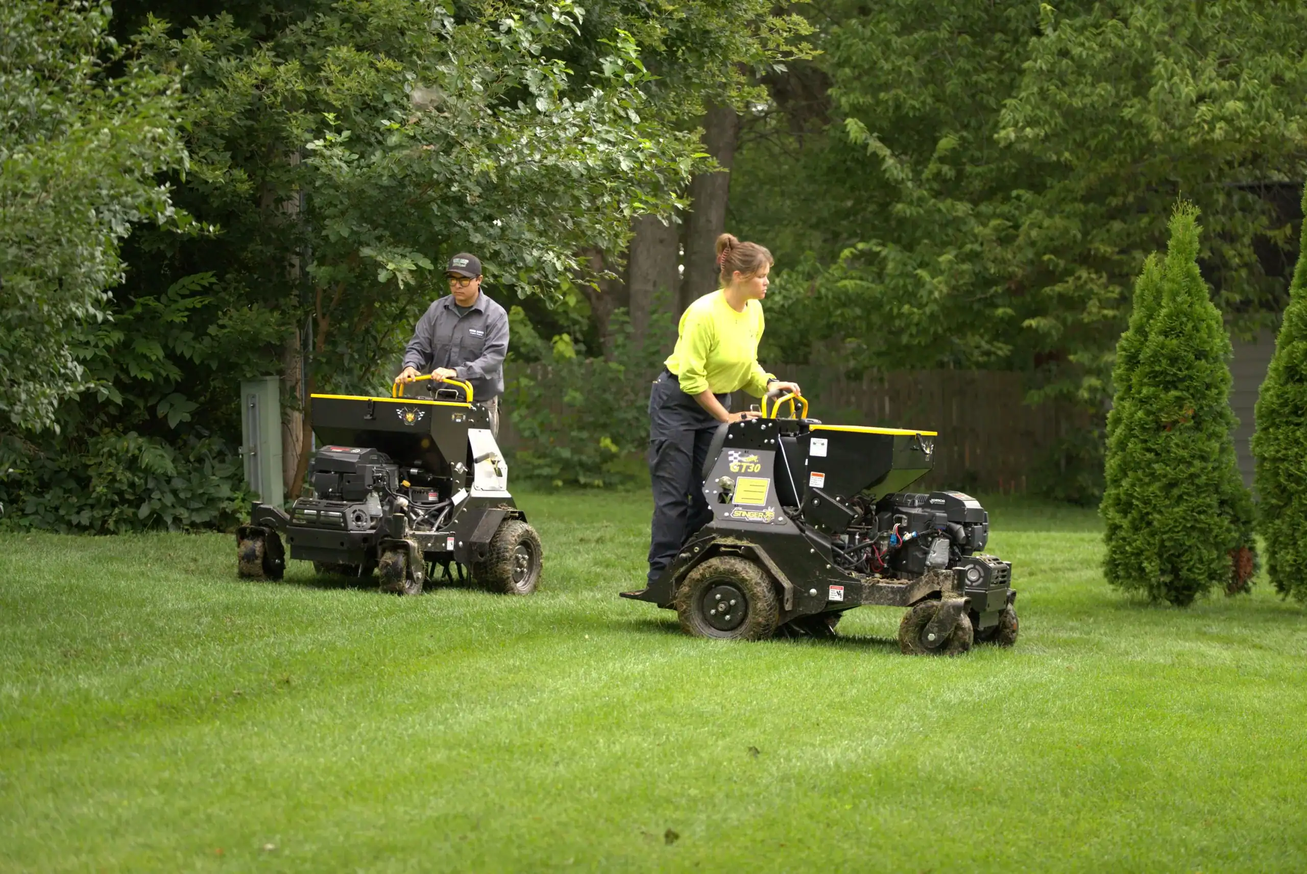 Green Acres landscaping crew performing professional lawn mowing service with commercial stand-on mowers on residential property