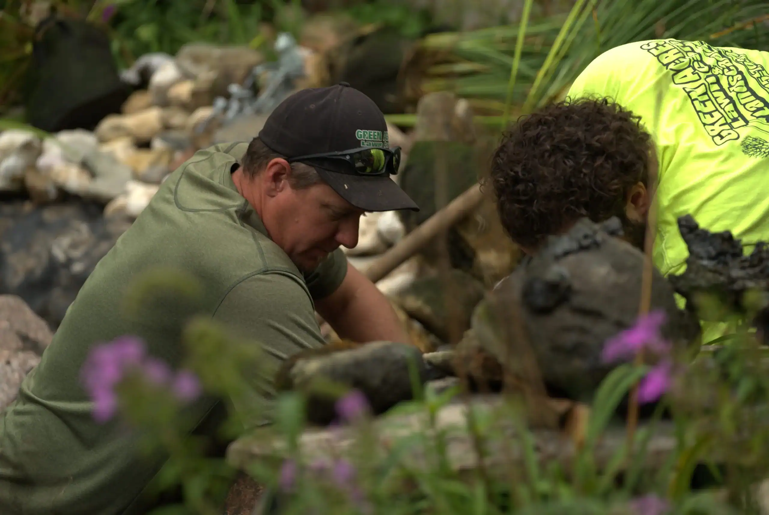 Green Acres crew members installing natural stone around decorative pond water feature