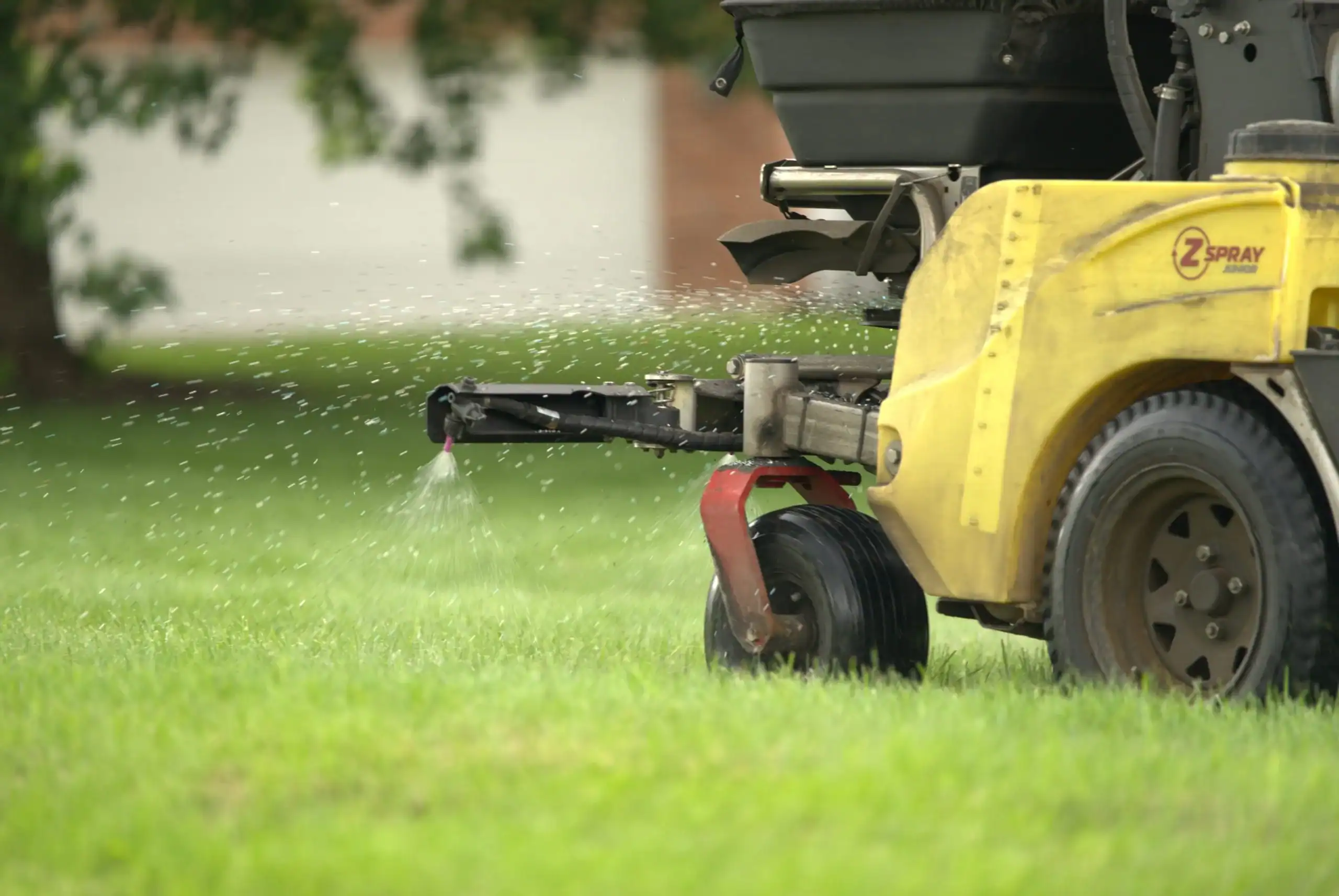 Green Acres Z-Spray stand-on aerator performing lawn aeration service on residential property