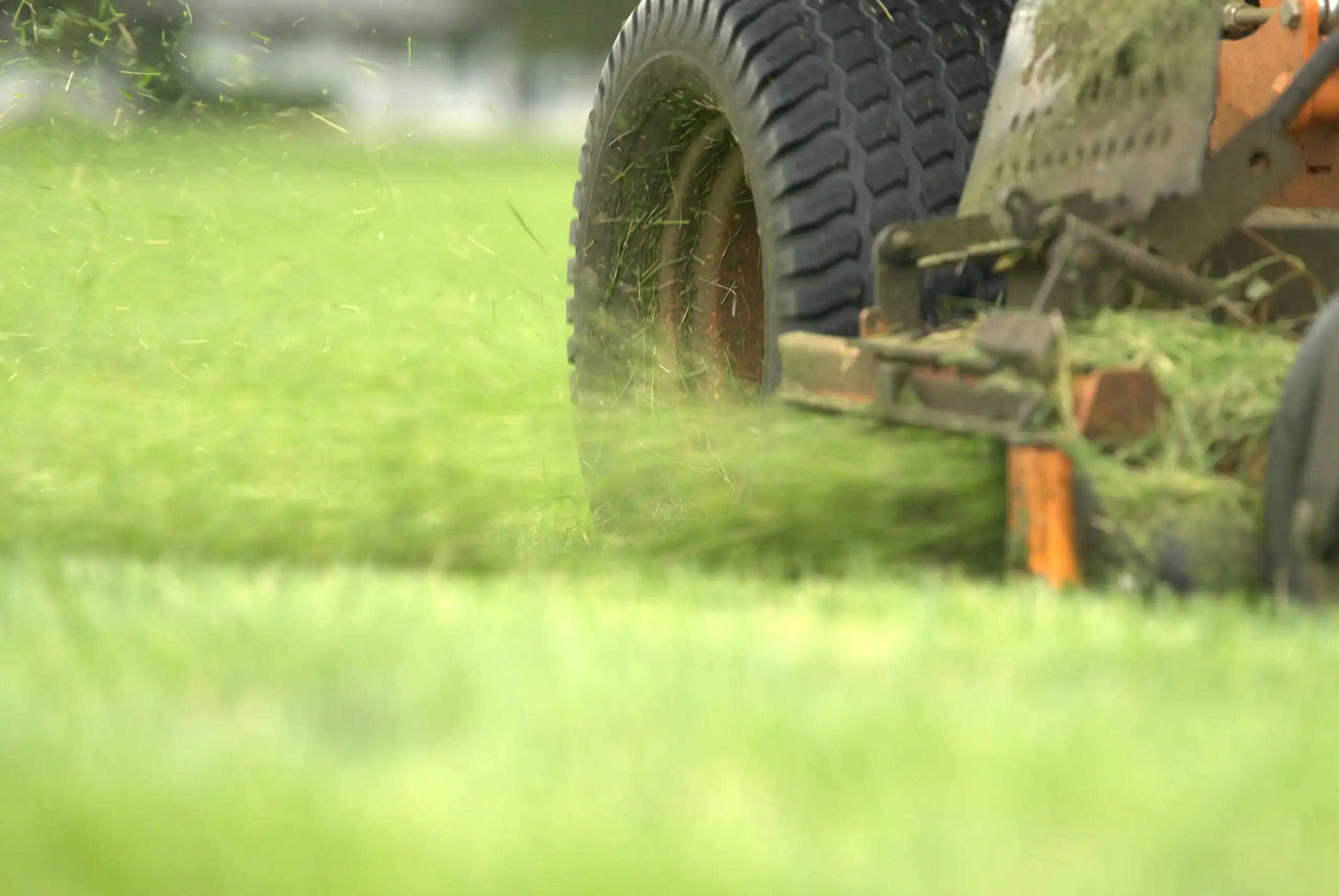 Green Acres commercial mowing equipment cutting residential lawn with grass clippings visible